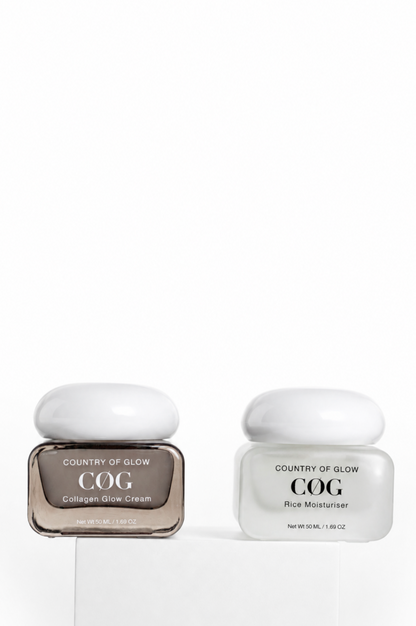 Two Country of Glow COG skincare jars on a white pedestal against a white background. The left jar is a square glass container with a white lid, containing Collagen Glow Cream in a brown-tinted bottle.